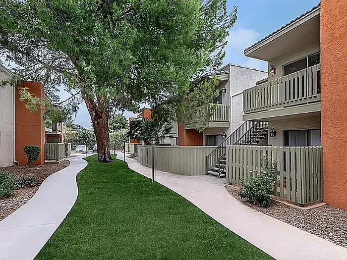 Beautiful apartment courtyard with lush green lawn, mature trees, picnic area, and charming pathway.