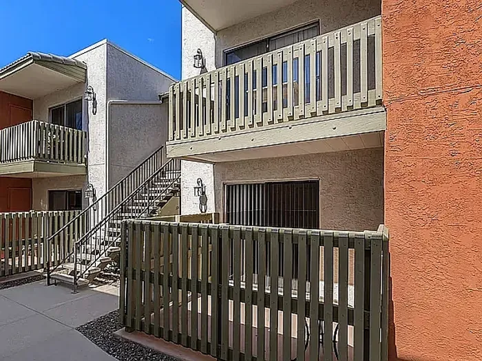 Beautiful apartment courtyard with lush green lawn, mature trees, picnic area, and charming pathway.