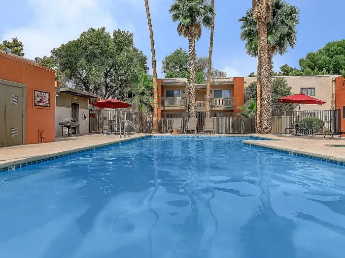 Beautiful apartment courtyard with lush green lawn, mature trees, picnic area, and charming pathway.