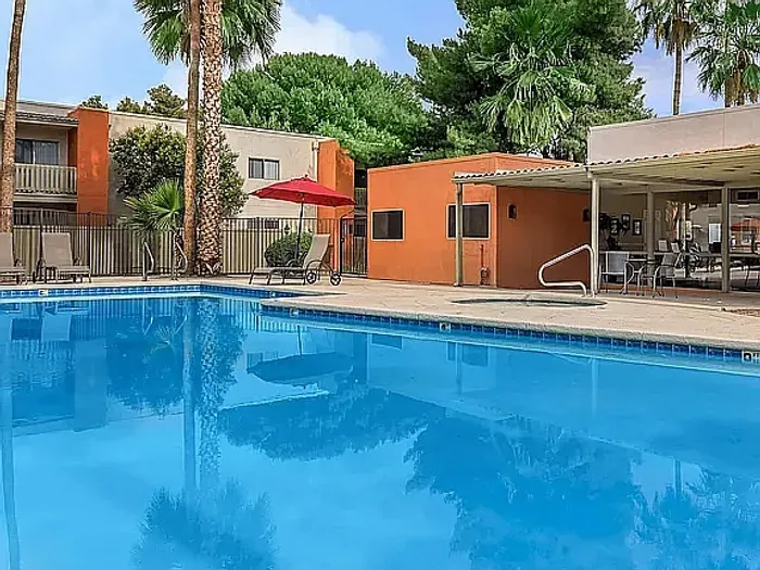 Beautiful apartment courtyard with lush green lawn, mature trees, picnic area, and charming pathway.