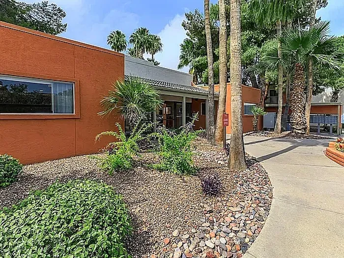 Beautiful apartment courtyard with lush green lawn, mature trees, picnic area, and charming pathway.