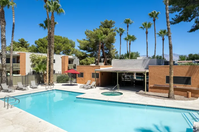 Inviting outdoor pool area with a luxurious hot tub, surrounded by comfortable lounge chairs and vibrant umbrellas, providing a perfect retreat for relaxation and leisure.