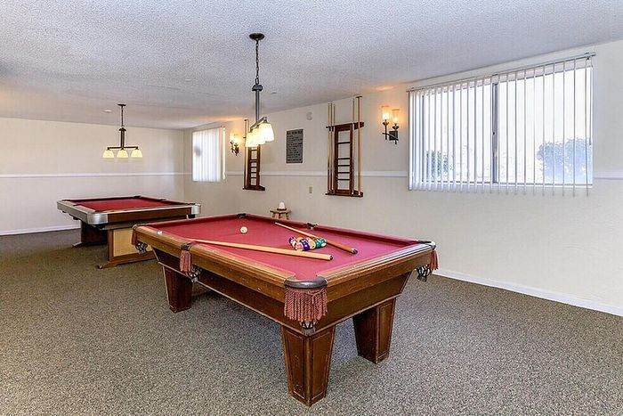 Charming game room featuring two elegant billiard tables under stylish pendant lighting, perfect for entertainment and leisure.