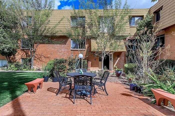 Charming apartment courtyard with lush greenery, cozy seating, and a serene atmosphere.