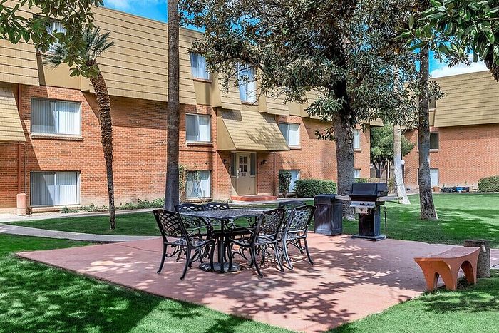 Charming apartment exterior with a lush courtyard featuring a picnic area and BBQ grill, perfect for outdoor gatherings and relaxation.