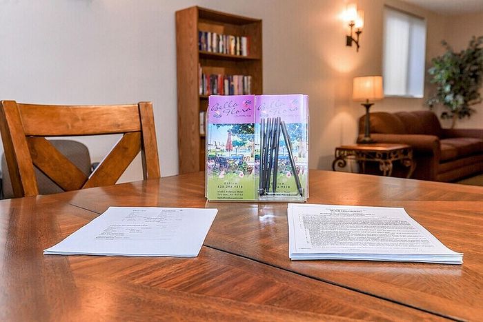 Inviting living area showcasing a cozy seating arrangement, elegant wooden table with brochures, ambient lighting, and a well-stocked bookshelf in the corner.
