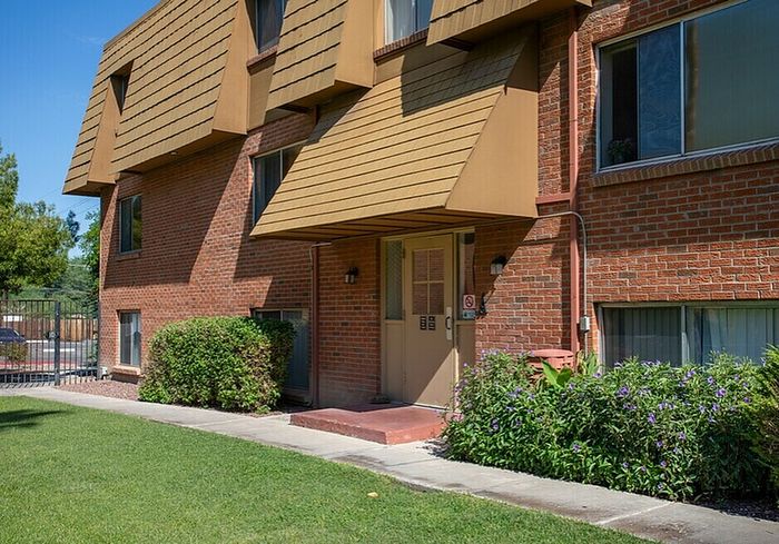 Charming brick apartment exterior with lush greenery and welcoming entryway.