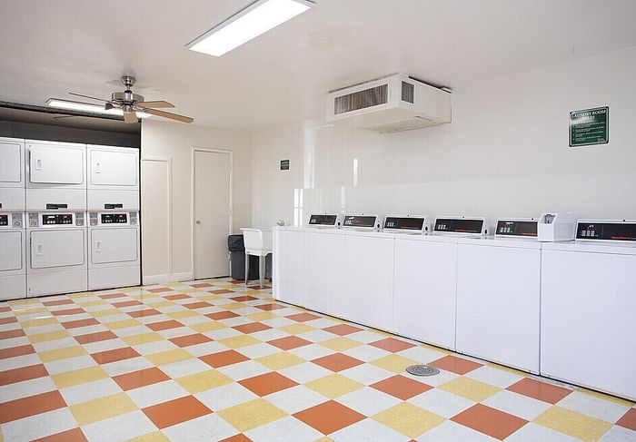 Spacious and bright laundry room with multiple washers and dryers, featuring vibrant checkered flooring and modern amenities.