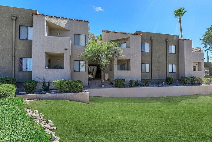 Charming two-story apartment building with modern design, lush green lawn, and vibrant landscaped surroundings.