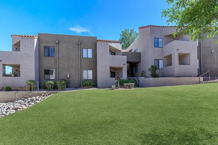 Charming modern apartment complex with vibrant green landscaping and spacious outdoor walkways.