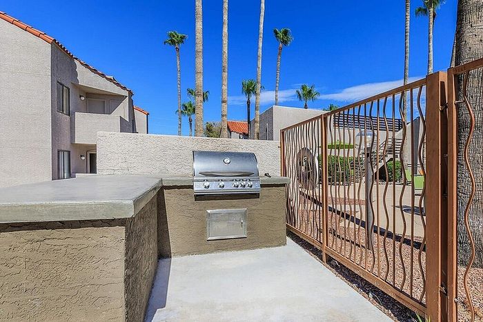 Vibrant outdoor space featuring a modern barbecue grill and lush palm trees, perfect for entertaining guests.