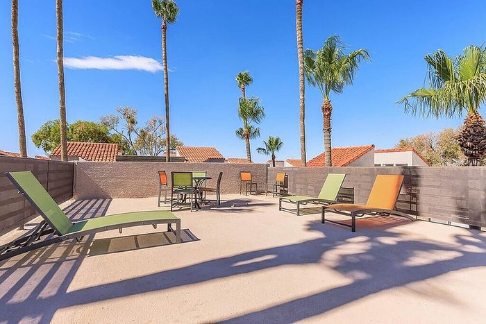 Sunny rooftop terrace with colorful lounge chairs and palm tree views, perfect for relaxation and enjoyment.