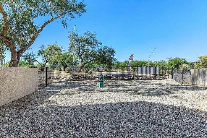 Spacious enclosed outdoor area with gravel flooring, mature trees, and a scenic view, offering tranquil privacy and natural beauty.