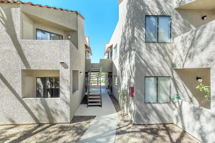 Modern apartment exterior showcasing textured walls, expansive balconies, and sunlit pathways.