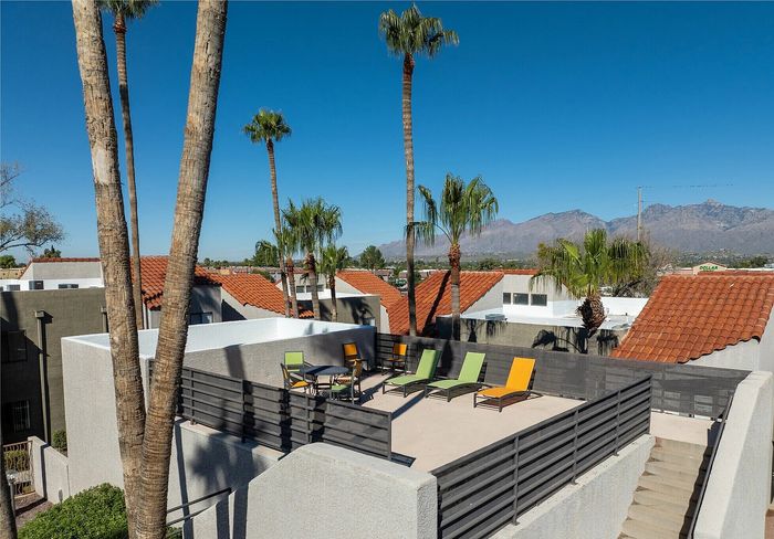 Chic rooftop patio featuring colorful lounge chairs with stunning mountain views and palm trees.