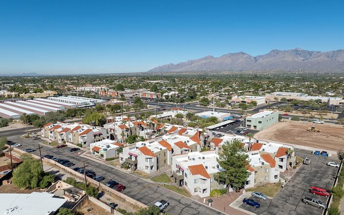 Aerial view of a charming residential complex with red-tiled roofs, surrounded by scenic mountain views and lush greenery.