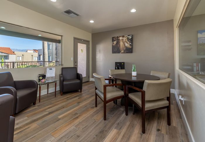 Chic office space featuring elegant seating, a wooden round table, and large windows with a scenic outdoor view.