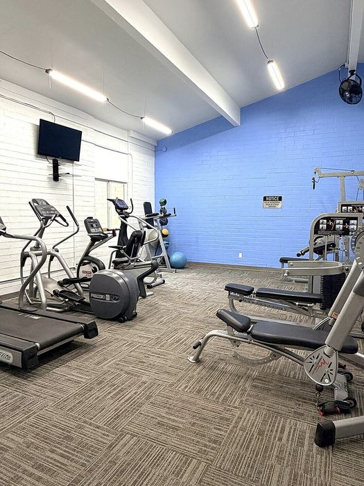 Modern fitness center with state-of-the-art treadmills, exercise bikes, and strength training equipment in a bright, inviting space.