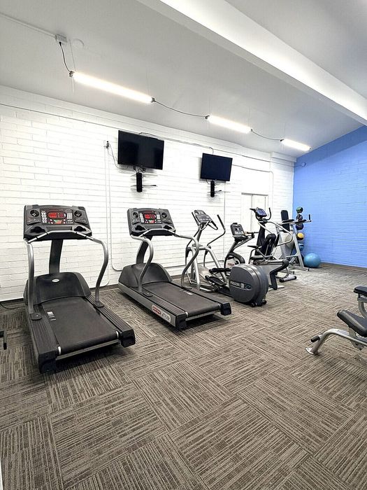 Modern fitness room with state-of-the-art treadmills, exercise bikes, and wall-mounted TVs for a complete workout experience.