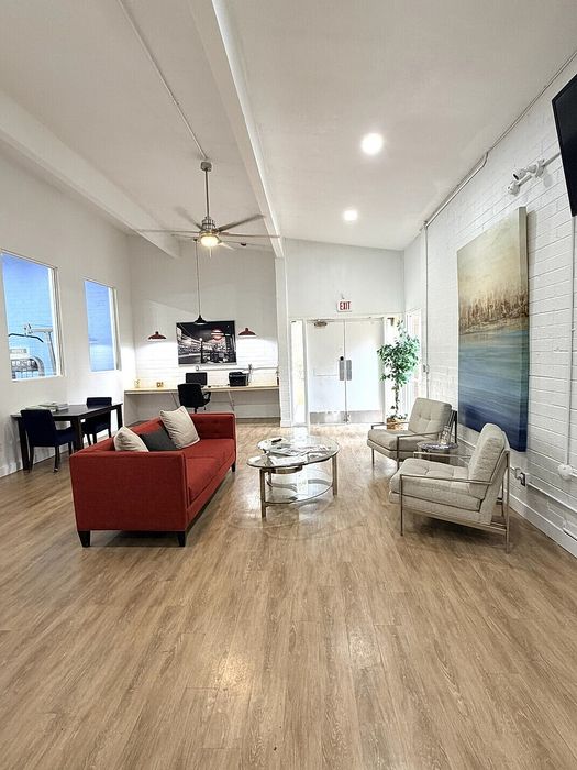 Contemporary lounge area featuring a vibrant red sofa, sleek hardwood floors, and modern decor under soft ambient lighting.