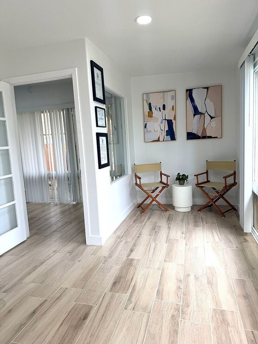 Bright and inviting sitting area with elegant wood flooring, modern art, and stylish directors&rsquo; chairs.