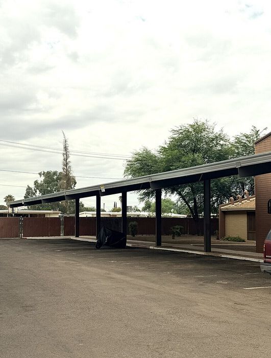 Charming covered parking area in a serene residential setting with lush greenery and ample space.