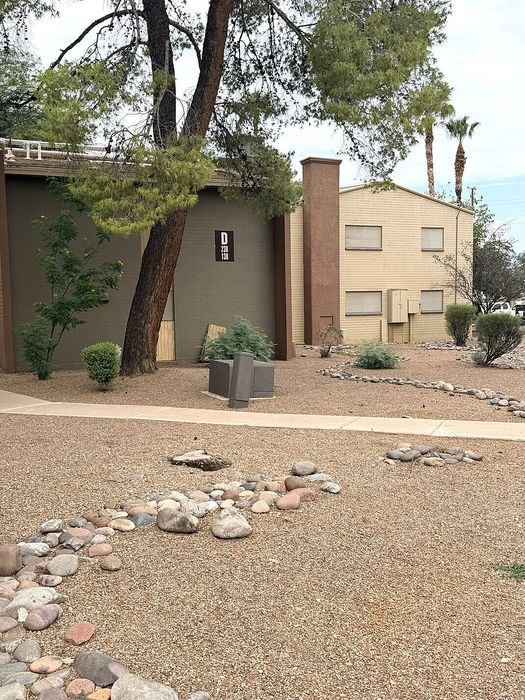 Charming apartment exterior with lush greenery and serene desert landscaping, ideal for tranquil living.