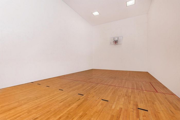 Modern indoor sports court with polished wooden floors and basketball hoop, ideal for active living.