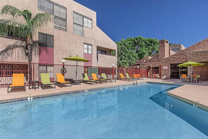 Vibrant poolside oasis with colorful lounge chairs and umbrellas, perfect for relaxation under clear blue skies.