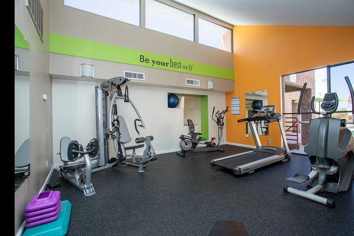 Vibrant apartment gym featuring modern exercise equipment, motivational decor, and large windows for ample natural light.