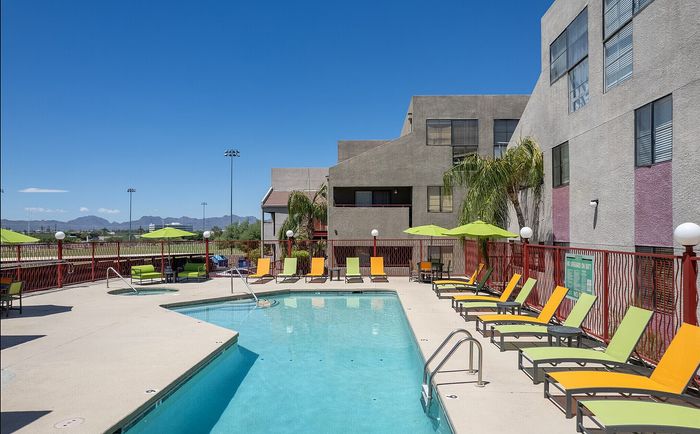 Inviting outdoor pool area with vibrant lounge chairs and umbrellas, set against scenic mountain views, perfect for relaxation and leisure.