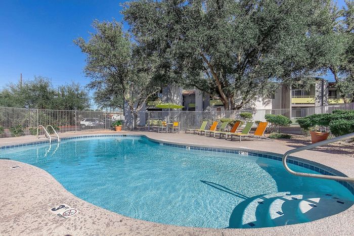 Inviting outdoor pool area with clear blue water, surrounded by lush greenery and vibrant lounge chairs for relaxation.