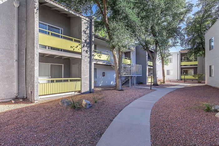 Charming apartment complex with modern balconies, surrounded by lush greenery and peaceful walkways.