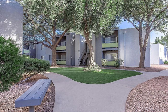 Charming apartment exterior with lush greenery, shaded walkways, and inviting outdoor spaces.