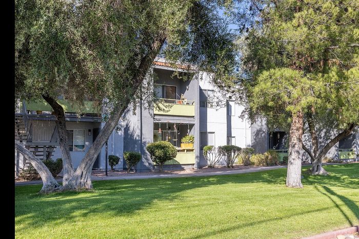 Charming apartment complex with lush green lawns and mature trees in a serene environment.