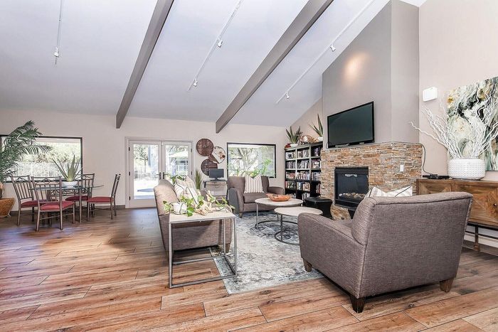 Elegant living space with high ceilings, featuring a cozy fireplace, modern sofa set, and a stylish dining area with natural light.