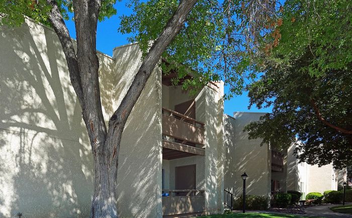 Charming apartment exterior with natural shade and lush green surroundings, highlighting serene living spaces.