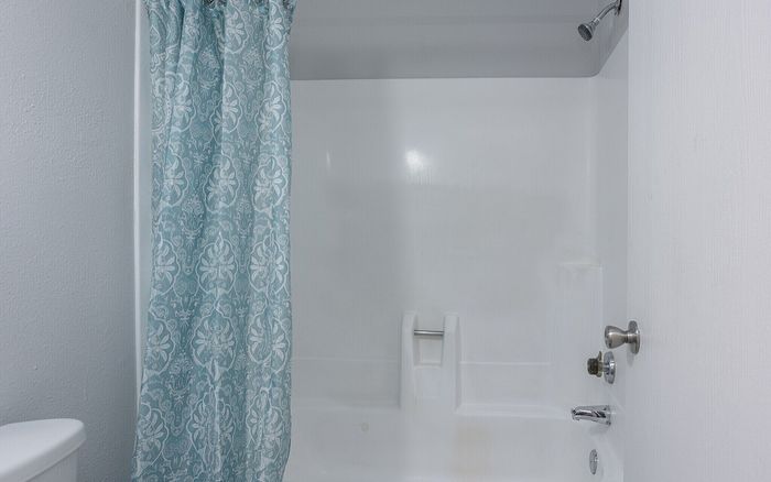 Elegant bathroom featuring a pristine white bathtub with a stylish teal patterned shower curtain.