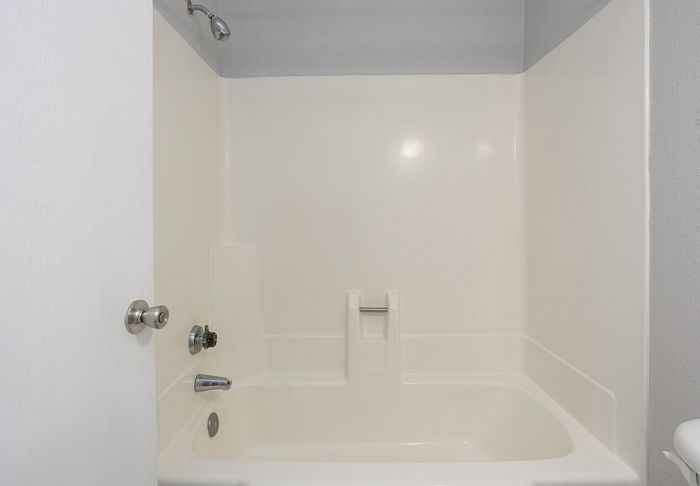 Elegant bathroom showcasing a pristine white bathtub with modern fixtures and clean lines, perfect for relaxation.