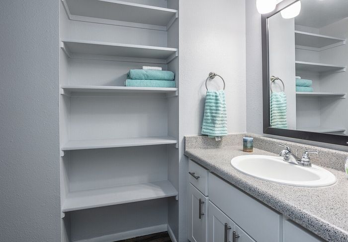 Bright modern bathroom with sleek open shelving, granite countertop, and stylish turquoise accents.