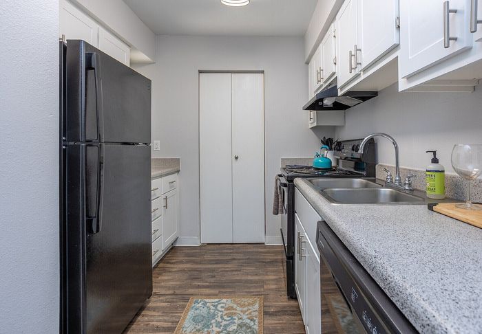 Modern kitchen with sleek black appliances, elegant white cabinetry, and polished countertops, offering a stylish and functional cooking space.