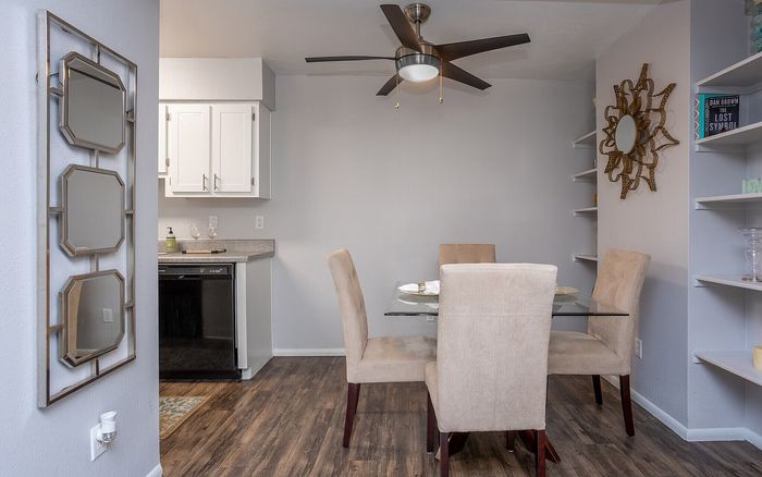 Elegant dining area with a glass table and plush beige chairs, complemented by a modern kitchen and stylish decor accents.