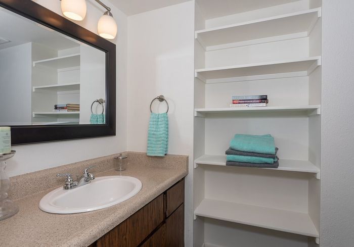 Modern bathroom with elegant countertop, spacious shelving, and soft teal accents creating a serene atmosphere.