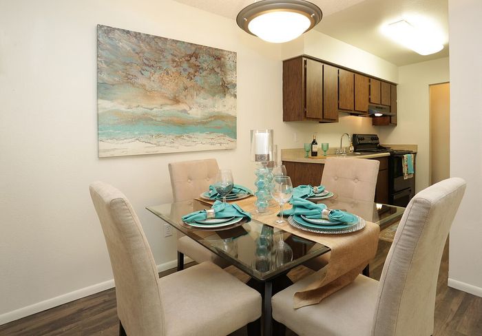 Chic dining area with elegant table setting and contemporary art next to a stylish kitchen, offering a warm and inviting ambiance.