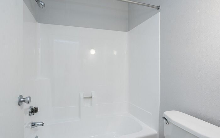 Modern bathroom with clean white bathtub and sleek fixtures, offering a fresh and inviting atmosphere.