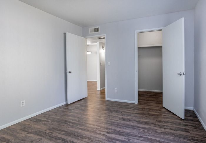 Bright, modern bedroom with sleek hardwood flooring and ample natural light, perfect for stylish living.
