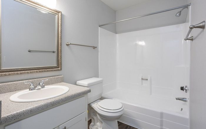 Modern bathroom featuring sleek fixtures, elegant mirror, and pristine bathtub with shower.