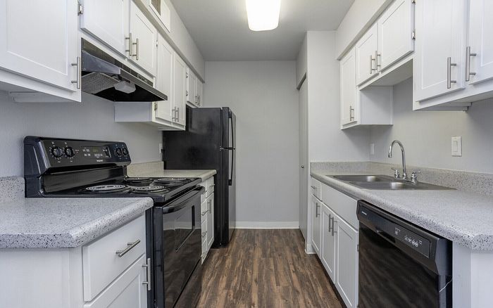 Contemporary kitchen with sleek white cabinetry, modern appliances, and elegant wood flooring.