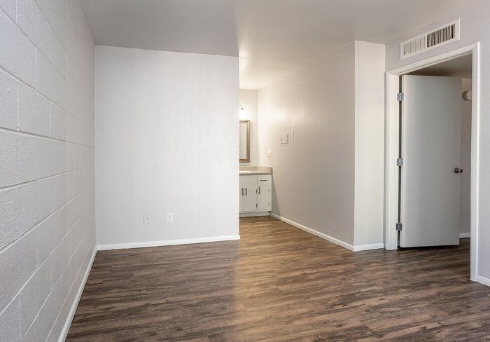 Modern apartment interior showcasing a bright, minimalist space with stylish wood flooring and neutral-toned walls, offering a perfect canvas for personalization.