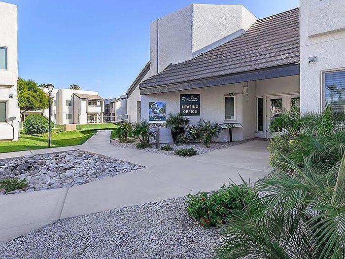 Inviting leasing office entrance surrounded by lush greenery in a modern apartment complex.